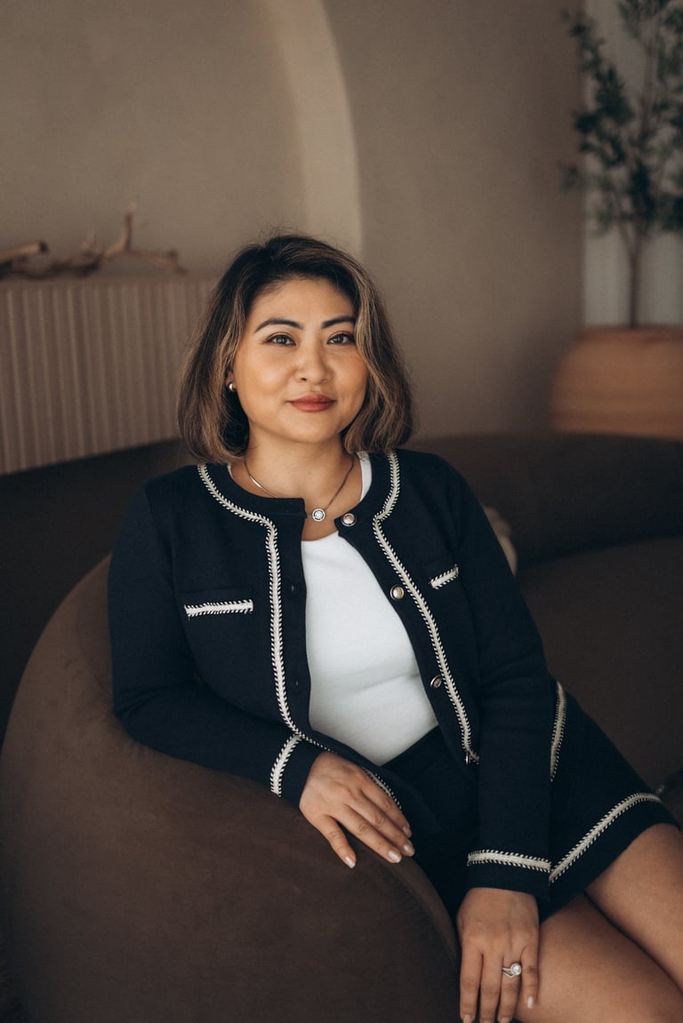 Woman in black and white trim blazer sitting on couch, looking upward in modern interior setting
